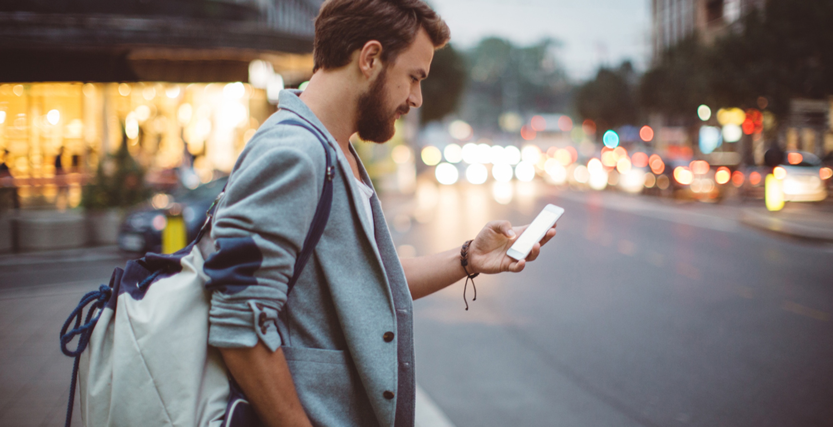 Man met rugtas kijkt op zijn smartphone